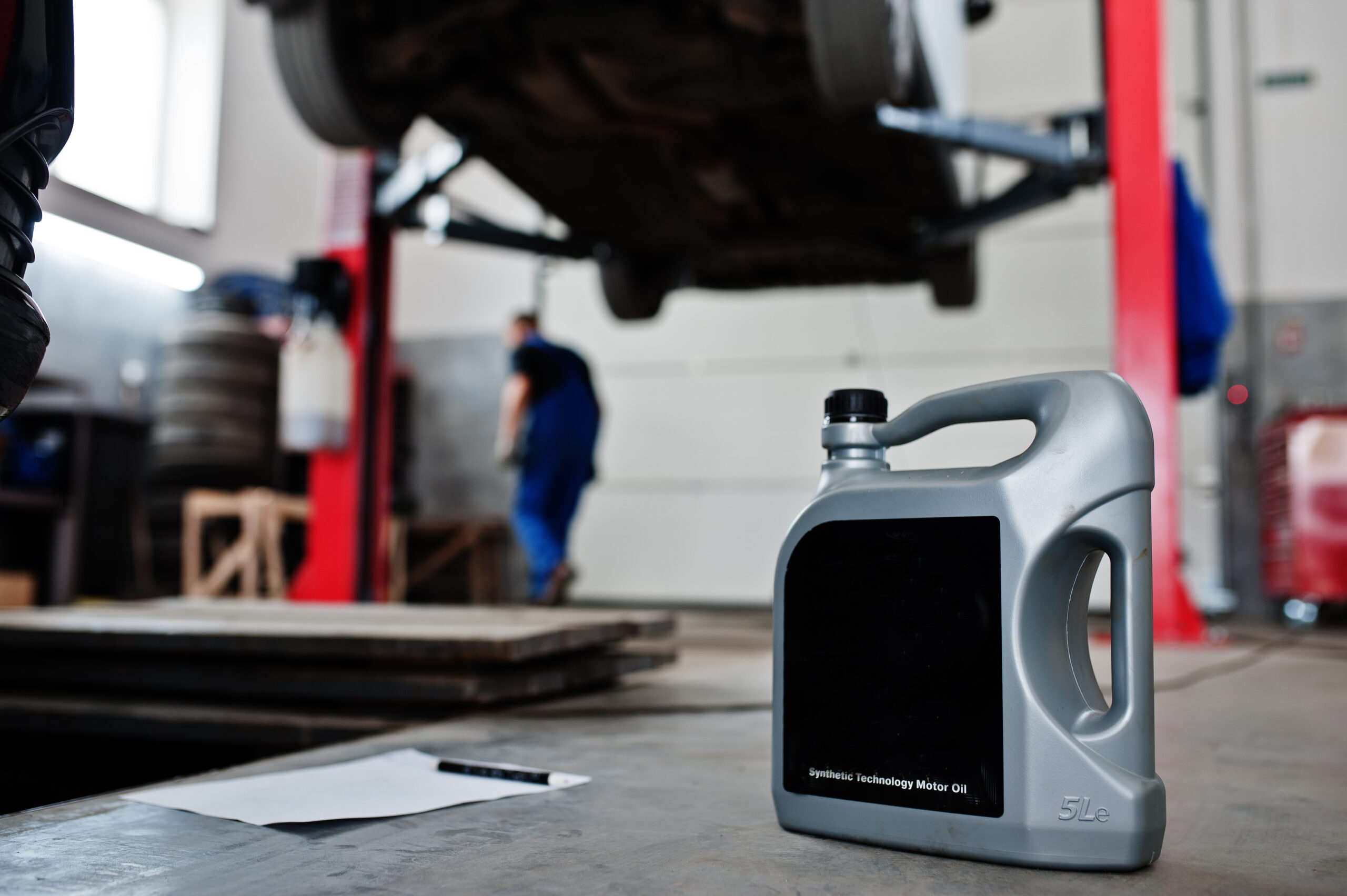 Car repair and maintenance theme. Gray plastic canister of motor oill in auto service.